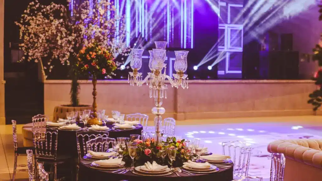 Empty banquet hall with purple stage lights, a candelabra centerpiece and a set round table