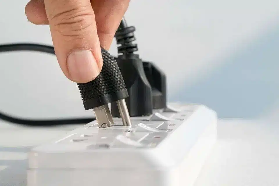 Hand plugging a black power cord into a white power strip