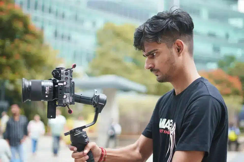 Videographer holding a camera on a handheld gimbal to film steady video