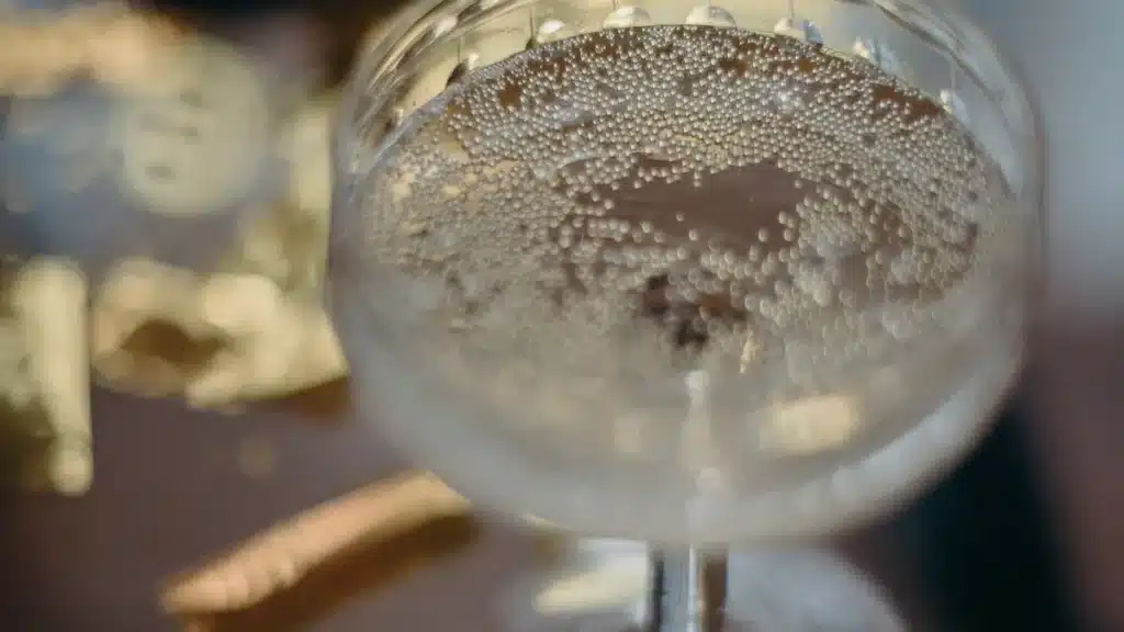 Champagne coupe with bubbles and gold confetti on a dark surface