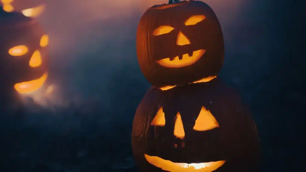 Carved jack-o'-lanterns glowing with candlelight on a dark night
