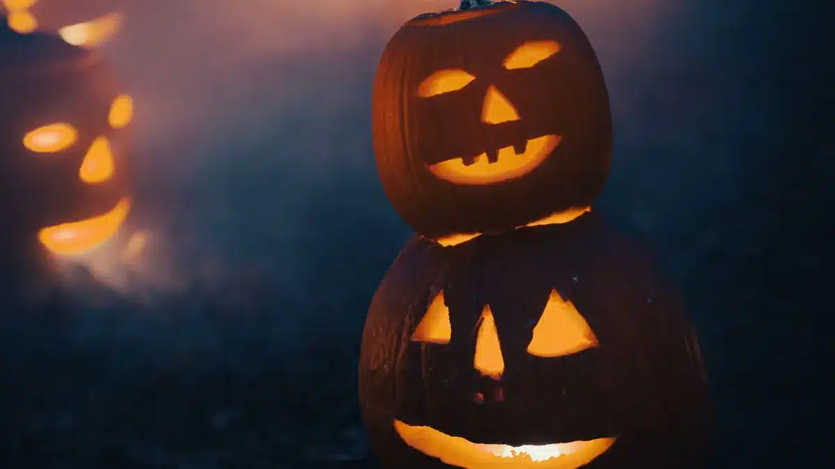 Carved jack-o'-lanterns glowing with candlelight on a dark night