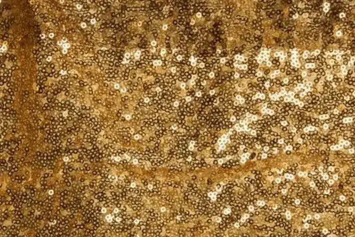 Close-up of shimmering dark gold sequin backdrop fabric