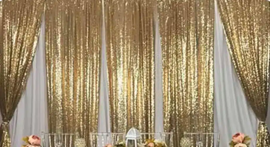 Gold sequin panels hung between white drapes behind a long table
