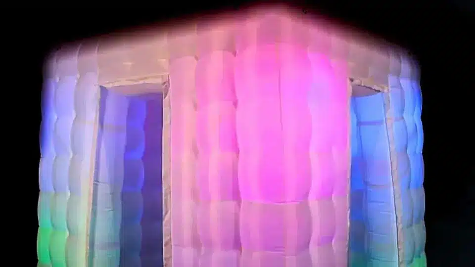Inflatable photo booth glowing pink, blue and green in a dark room
