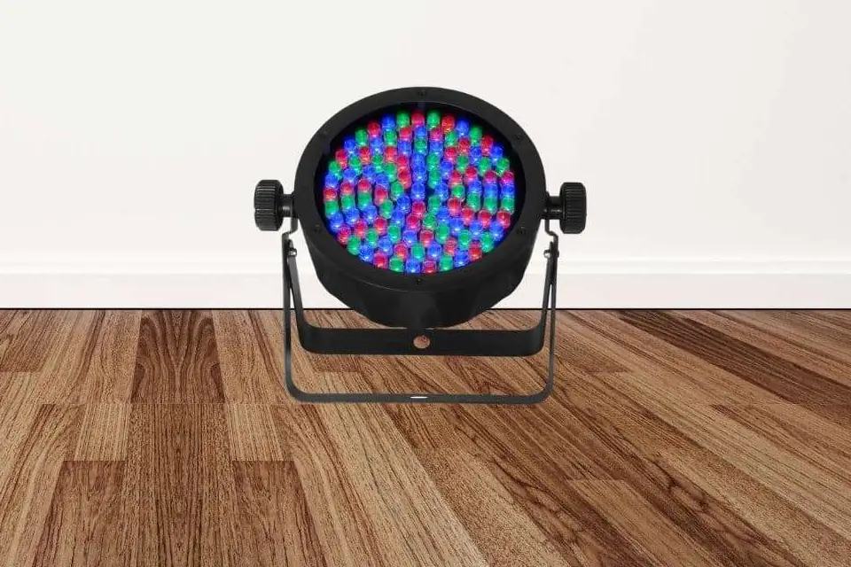 LED uplight with multicolored bulbs standing on a wooden floor in front of a white wall