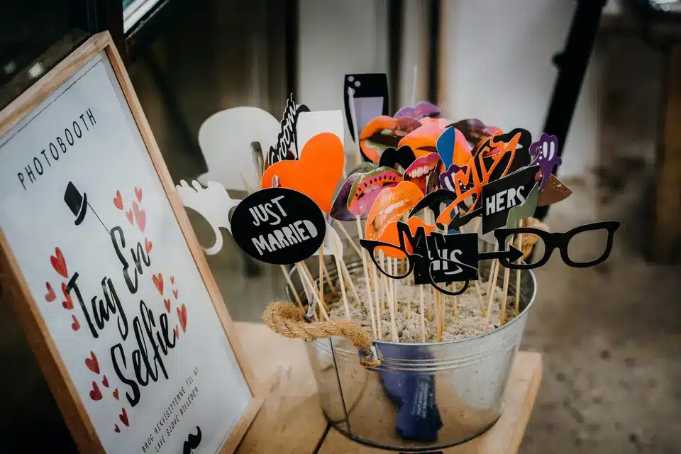 Photo booth props on sticks in a metal bucket beside a framed photo booth sign
