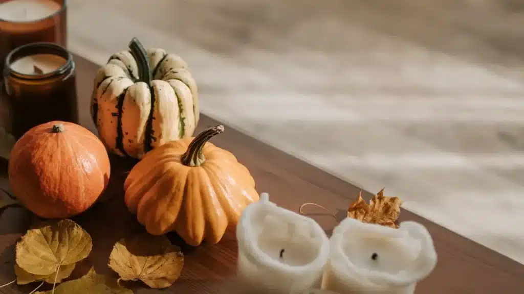 Pumpkins, a striped gourd, candles and autumn leaves on a wooden table