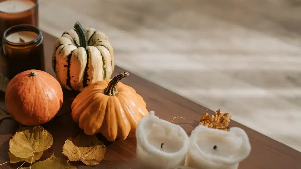 Pumpkins, a striped gourd, candles and autumn leaves on a wooden table