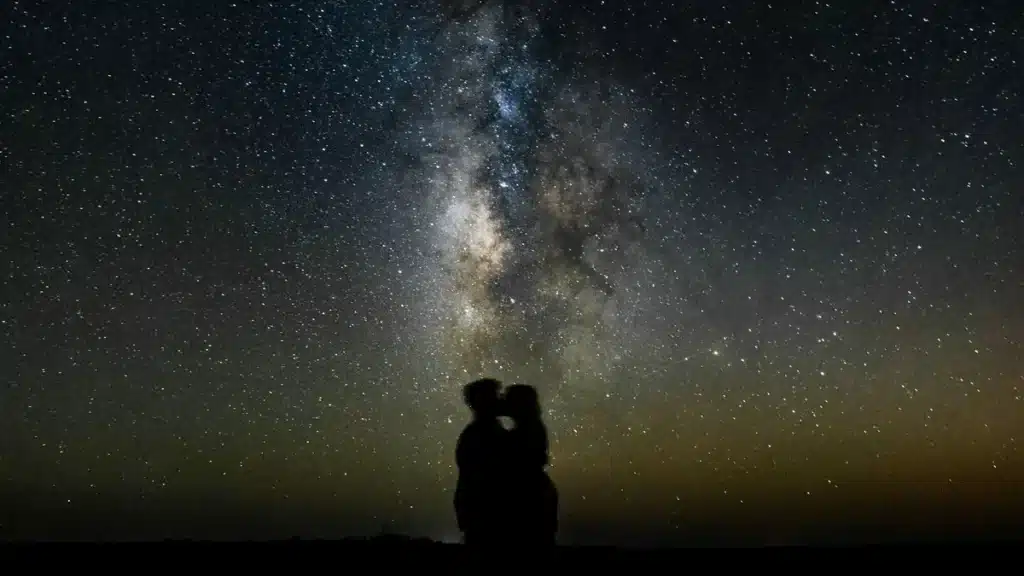 Silhouette of a couple embracing under a star-filled night sky with the Milky Way overhead