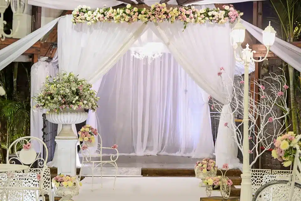 Ceremony canopy draped in sheer white fabric and topped with pink and white flowers