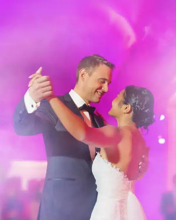Bride and groom sharing a first dance under pink uplighting